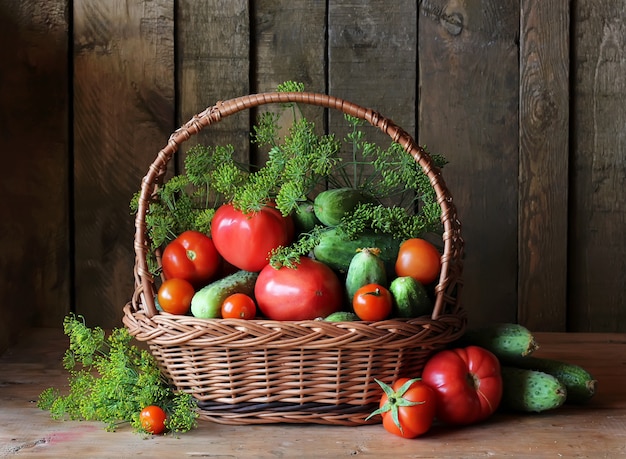 Fresh vegetables: tomatoes, cucumbers and dill in basket on the table from the boards. 