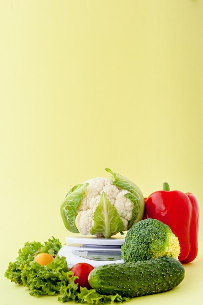 黄色の背景の花瓶に新鮮な野菜。健康的な食事、ダイエット計画、減量、デトックス、有機農業の概念。
