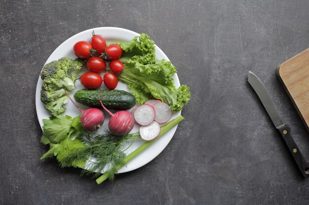 Fresh vegetables in a white plate on a gray table