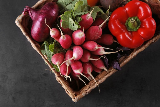 Fresh vegetables in wicker basket on dark background top view