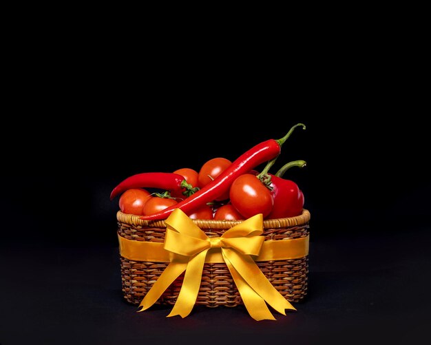 Fresh vegetables in a wicker basket tied to onions on a black background