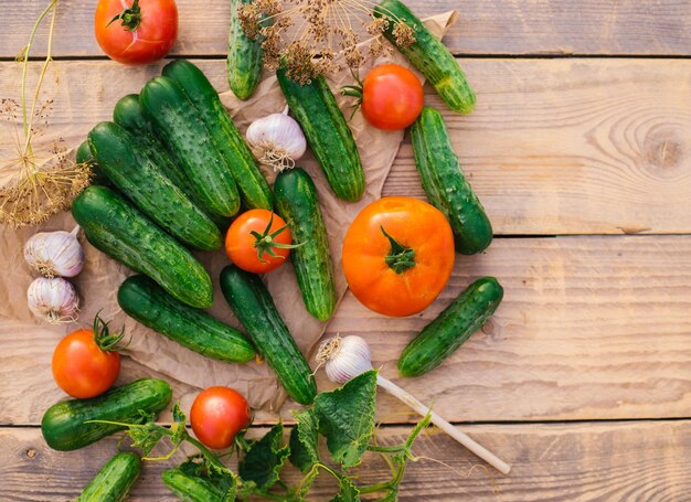 Fresh vegetables on a wooden background The concept of healthy eating Cucumbers tomatoes garlic dill Top view