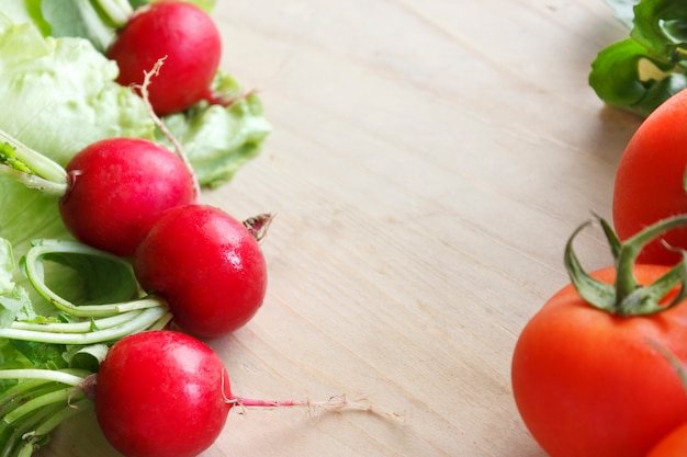 Photo fresh vegetables on a wooden board - radish, lettuce, arugula, tomatoes