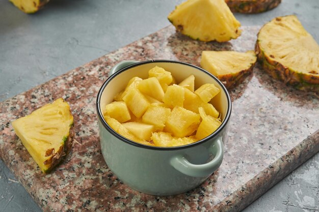 Foto pezzi di ananas freschi e vivaci su una base grigia per una dieta sana e disintossicante