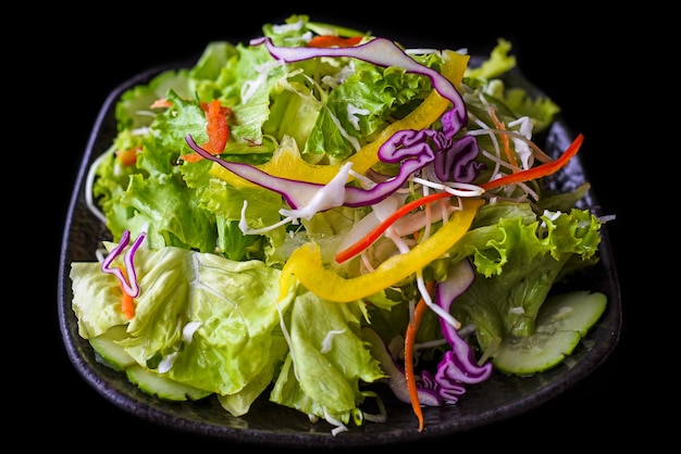 Свежий вьетнамский салат с овощами на черном фоне, вид сбоку