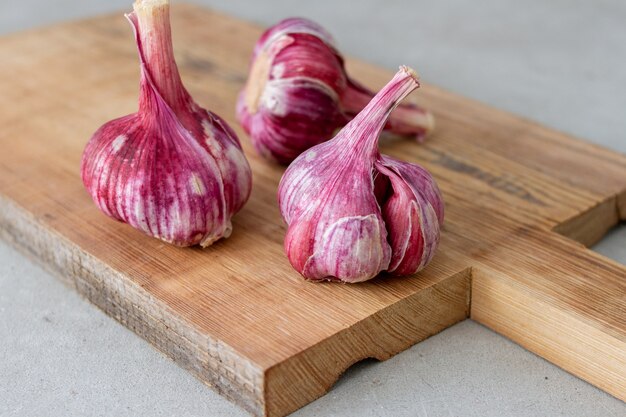 Fresh violet garlic bulbs on wooden cutting board