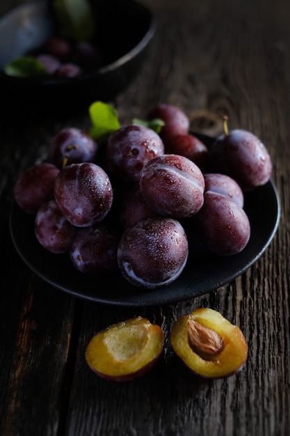 Fresh violet plums at dark wooden table background