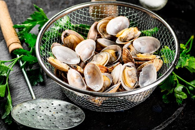 Fresh vongole in a colander on a stone board with parsley