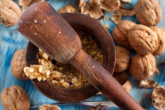 Fresh walnuts with mortar and pestle on a blue wooden table close up