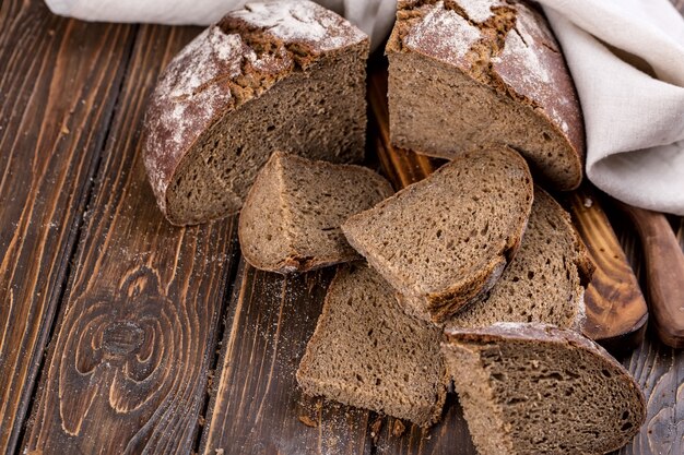 Свежий теплый хлеб, нарезанный кусочками на старом деревянном столе, с салфеткой