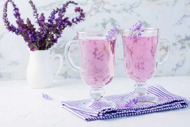 Fresh water with lavender in glasses and a bouquet of flowers in a jug on the table. Lavender aromatic cocktail