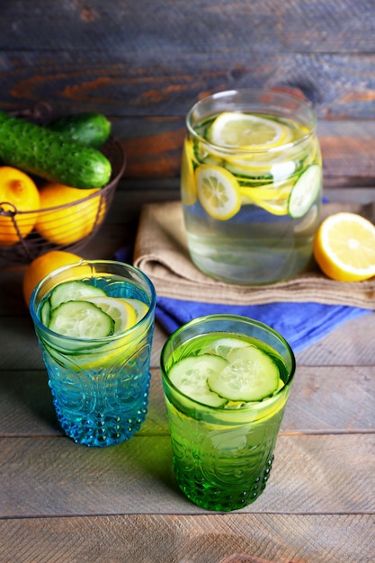 Fresh water with lemon and cucumber in glassware on wooden background