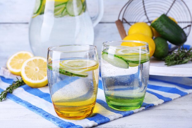Fresh water with lemon and cucumber in glassware on wooden table closeup