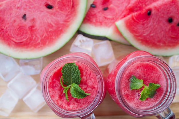 Fresh watermelon juice is in a glass and sliced watermelon on the plate.