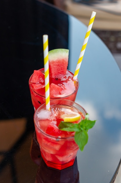 Fresh watermelon juice with mint and ice in the glass on glass\
table. sweet summer dessert,cocktail healthy food concept, close\
up. summertime. selective focus.