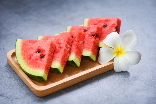 Fresh watermelon slice and white flower on wooden tray