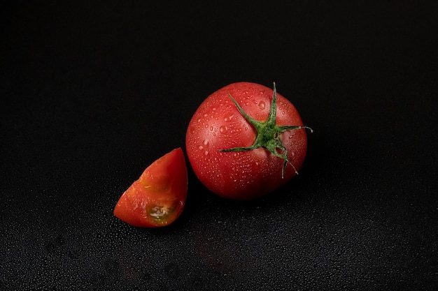 Fresh wet tomatoes on a black background sliced tomatoes