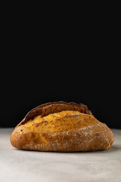 Fresh wheat bun on a light table on a black background