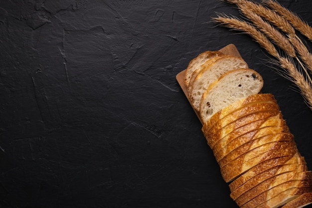 Fresh wheaten baton bread on dark background Top view Copy space