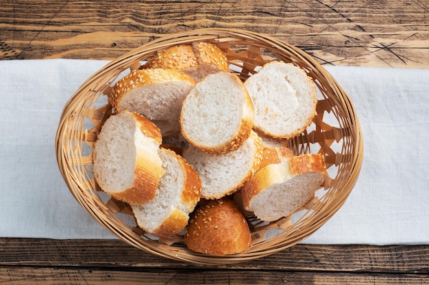 Fette di baguette di pane bianco fresco in un cesto di vimini sfondo tavolo rustico in legno close up