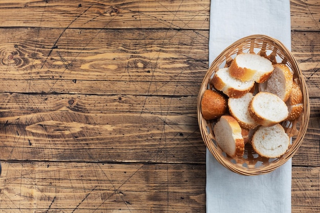 Foto fette di baguette di pane bianco fresco in un cesto di vimini sfondo di tavolo rustico in legno spazio per copiare