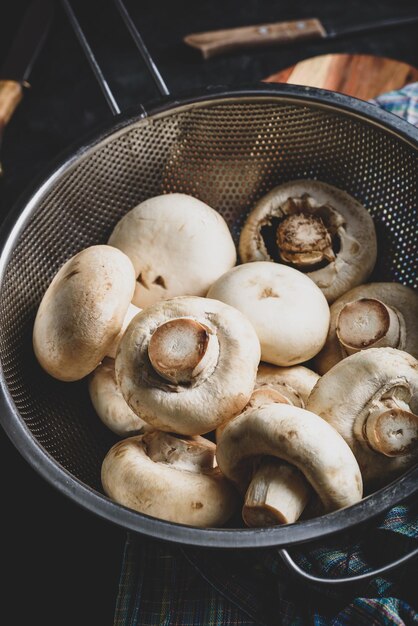 Fresh white button mushrooms in metal colander