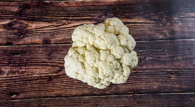 Fresh white cauliflower with green leaves on wooden table