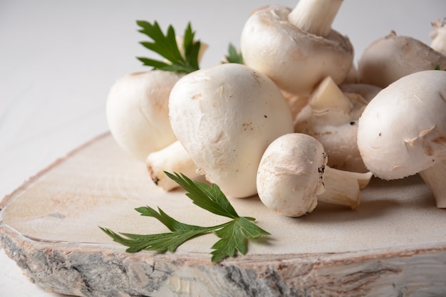 Fresh white champignon mushrooms on wooden board