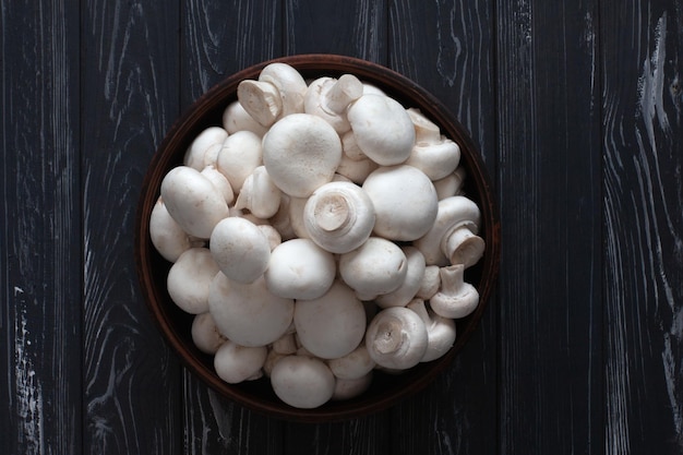 Fresh white champignons on a gray wooden table in a bowl top view Vegetables for cooking delicious dishes