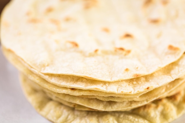 Fresh white corn tortillas on a white paper.