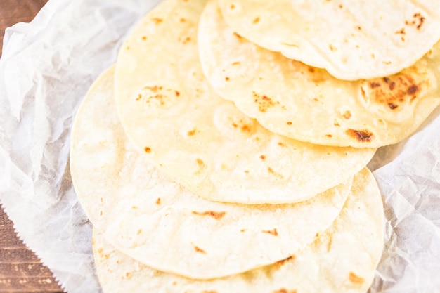 Fresh white corn tortillas on a white paper.