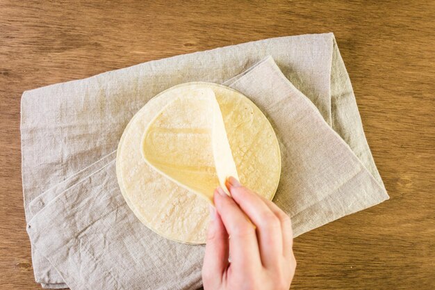 Fresh white corn tortillas on a wood background.