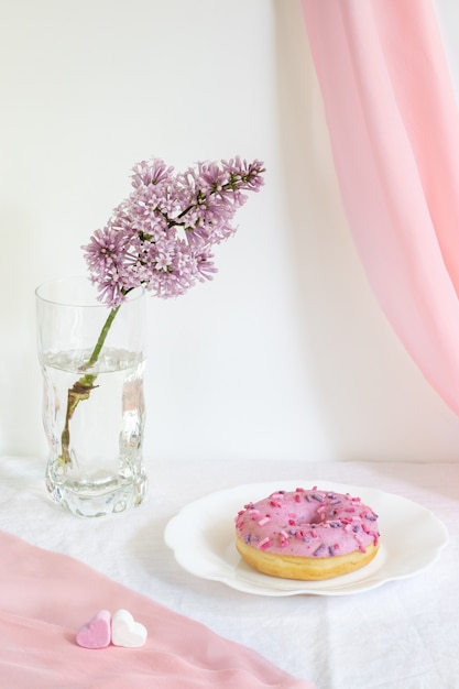 Fresh white glazed donut on curly plate on white background