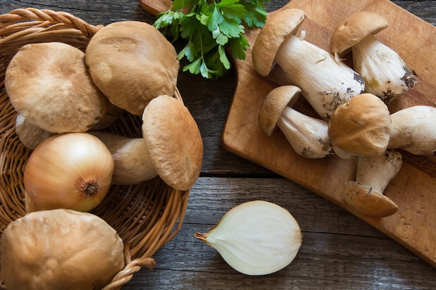 Fresh white mushrooms in basket and ingredients for mushroom's cream-soup on wooden board.