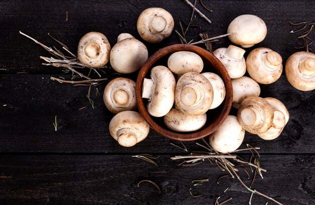 Fungo prataiolo bianco fresco dei funghi su di legno nero. vista dall'alto. copia spazio.