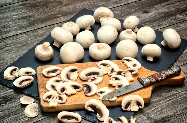 Fresh white mushrooms on a stone background. Champignons de Paris cut in pieces.