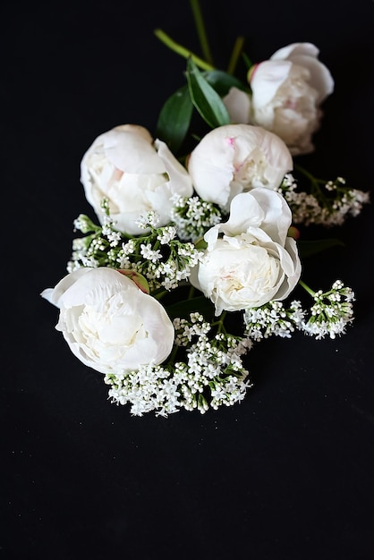 Foto peonie bianche fresche su sfondo nero scuro un biglietto di condoglianze data del matrimonio un invito a una vacanza congratulazioni uno spazio vuoto per il testo vista dall'alto era disteso