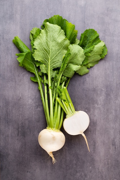 Fresh white round turnip radish on white surface.