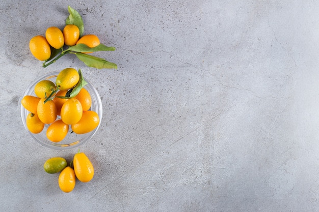 Fresh whole citrus cumquat fruits with leaves placed in bowl