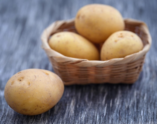 Fresh whole potatoes in a basket on textured surface