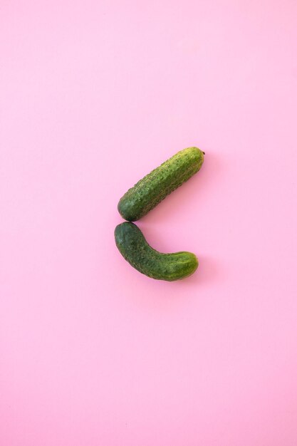 Fresh whole ripe cucumbers on pink background