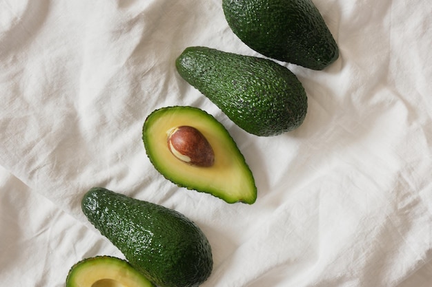 Fresh whole and sliced avodcado fruit on light background