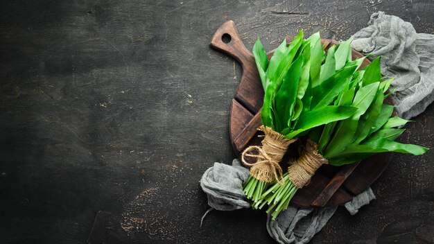 Photo fresh wild garlic leaves on a wooden background top view free space for your text