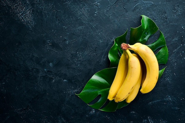 Fresh yellow bananas on a black stone table Top view Free copy space