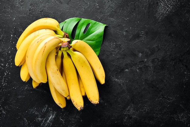 Fresh yellow bananas on a black stone table Top view Free copy space