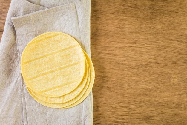 Fresh yellow corn tortillas on a wood background.