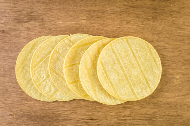 Fresh yellow corn tortillas on a wood background.