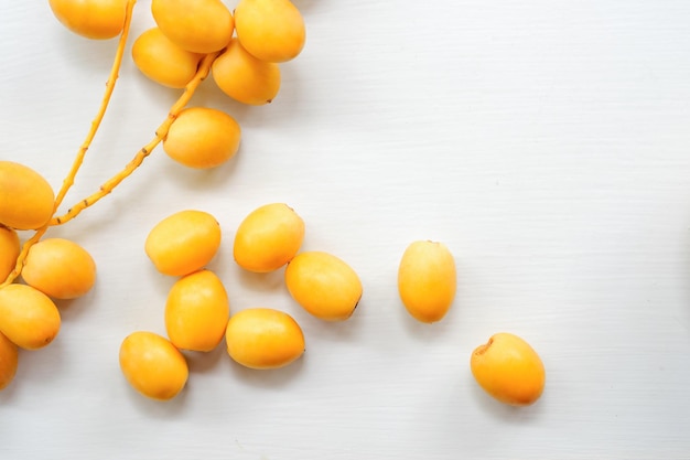 Fresh yellow dates on a white wooden floor top view