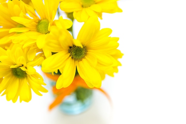 Fresh yellow flowers in a small bouquet in glass jar.