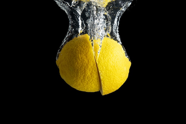 Fresh yellow lemon in water splash isolated on black.